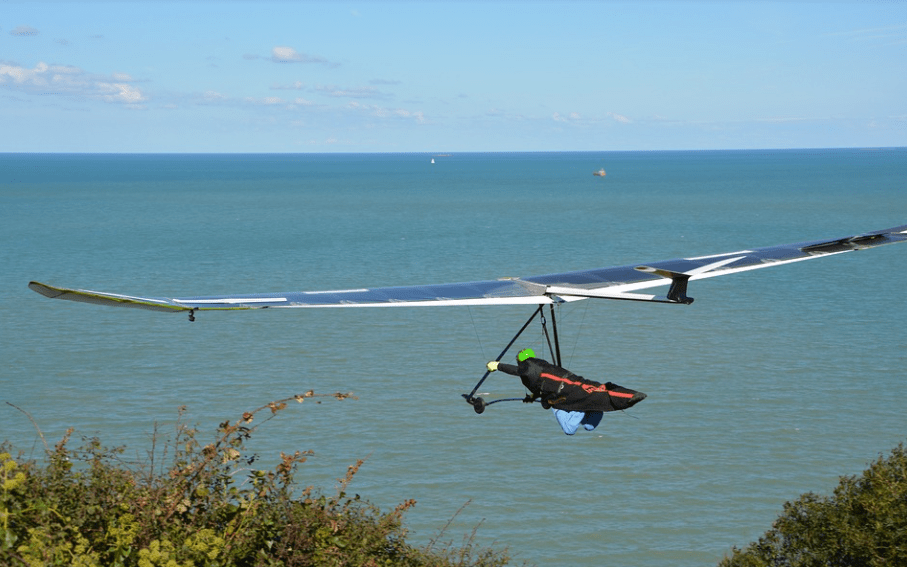 blue hang glider, blue sea, glider wearing black gear