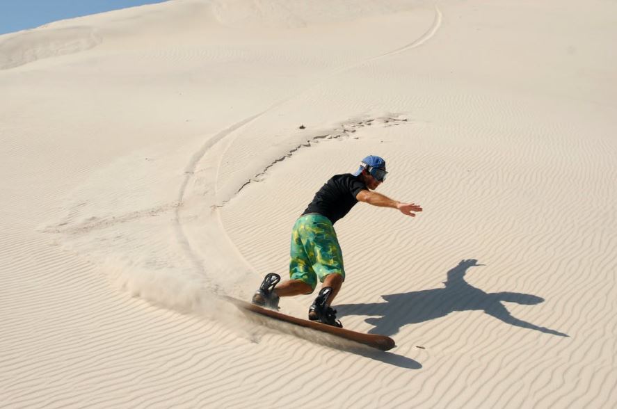 A man sandboarding in desert