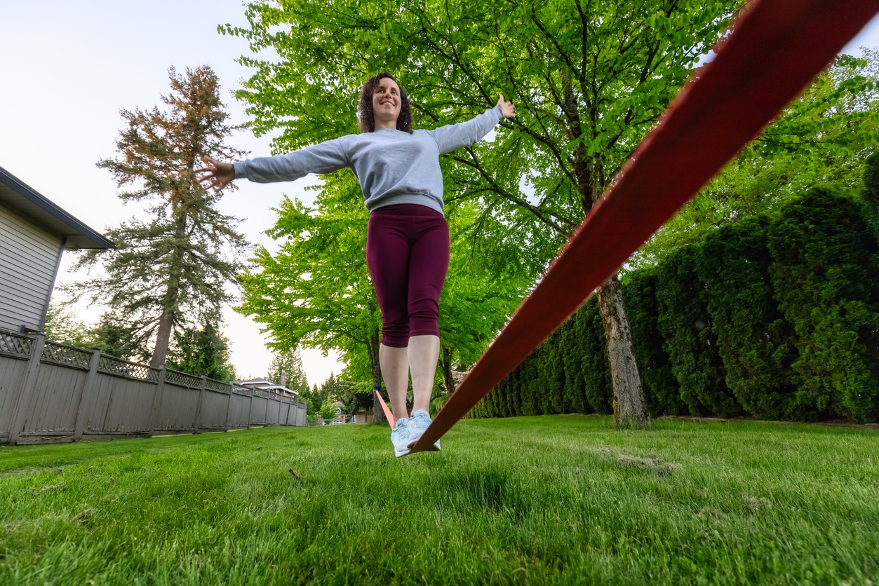 Adventurous White Caucasian Adult Woman walking on a Slackline