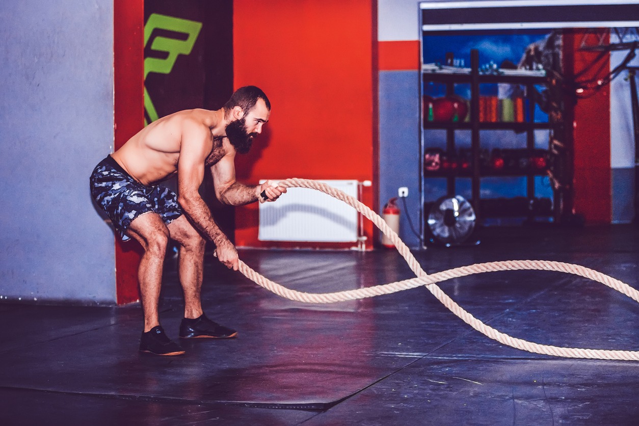 Bearded man working out with battle ropes at gym