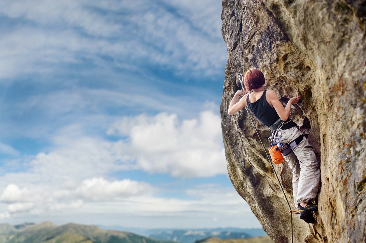 Female rock climber on steep overhanging rock cliff