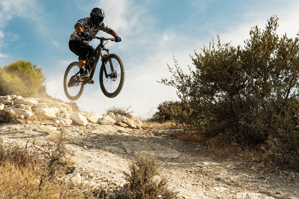 Professional bike rider jumping during downhill ride
