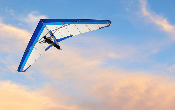 a hang gliding flying at sunset