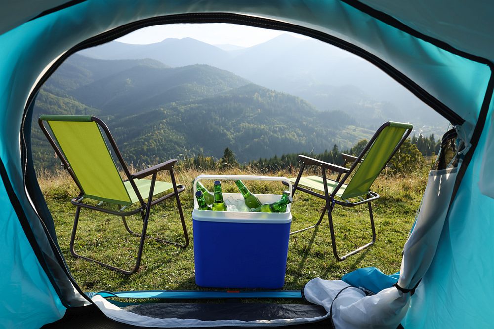 Chairs and cooler box with bottles of beer on top of a mountain
