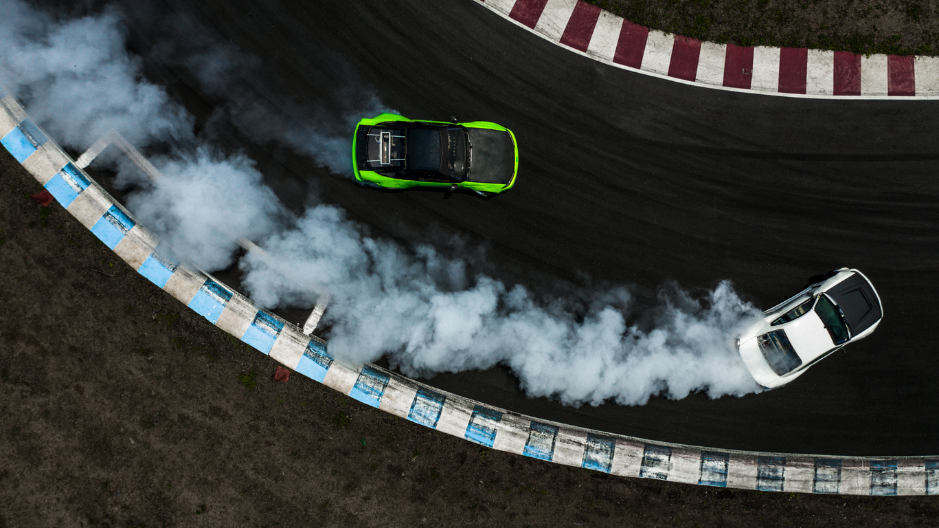 Two cars on a drifting battle in  race track with smoke