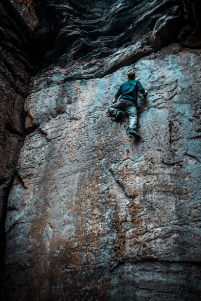 a man with a blue jacket climbing a mountain