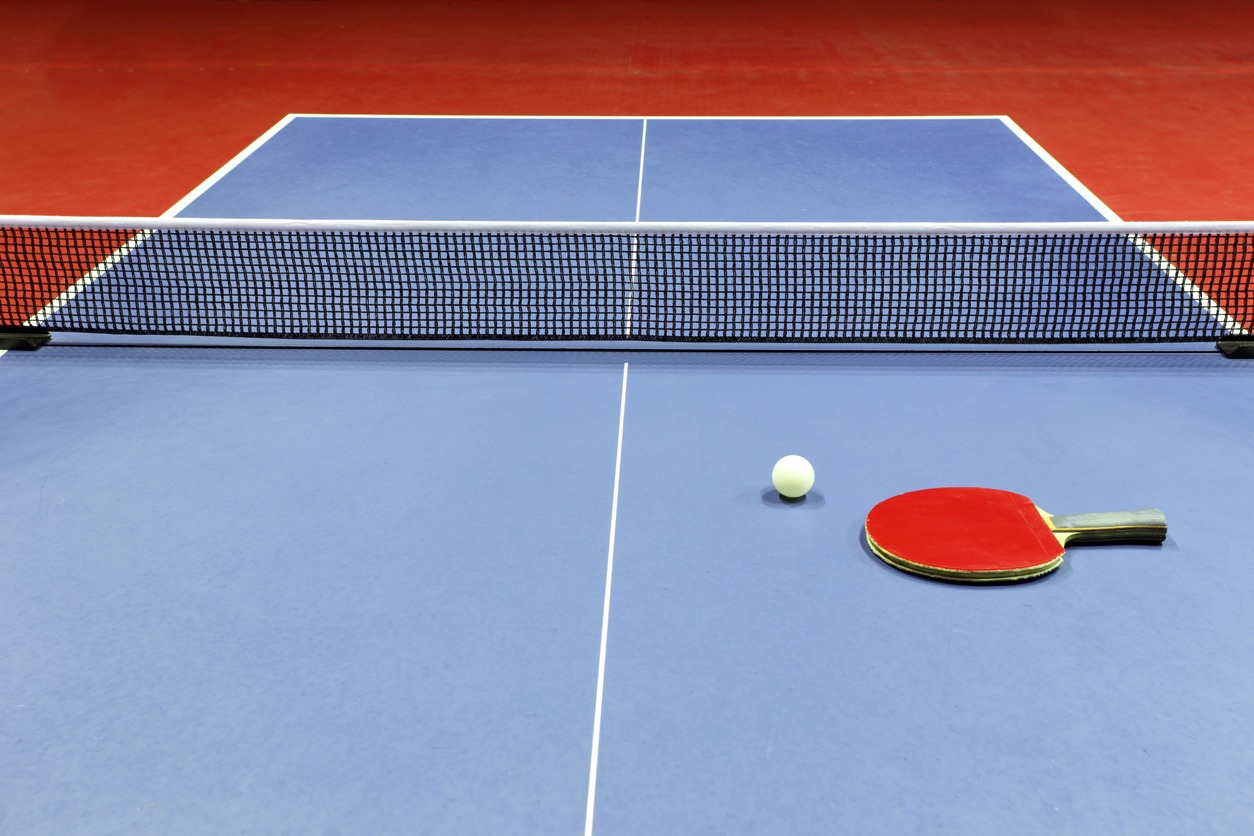 Close-up of blue ping pong table with red paddle on top