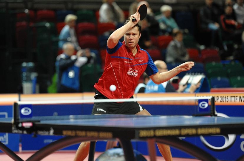 a man with his hand raised playing table tennis
