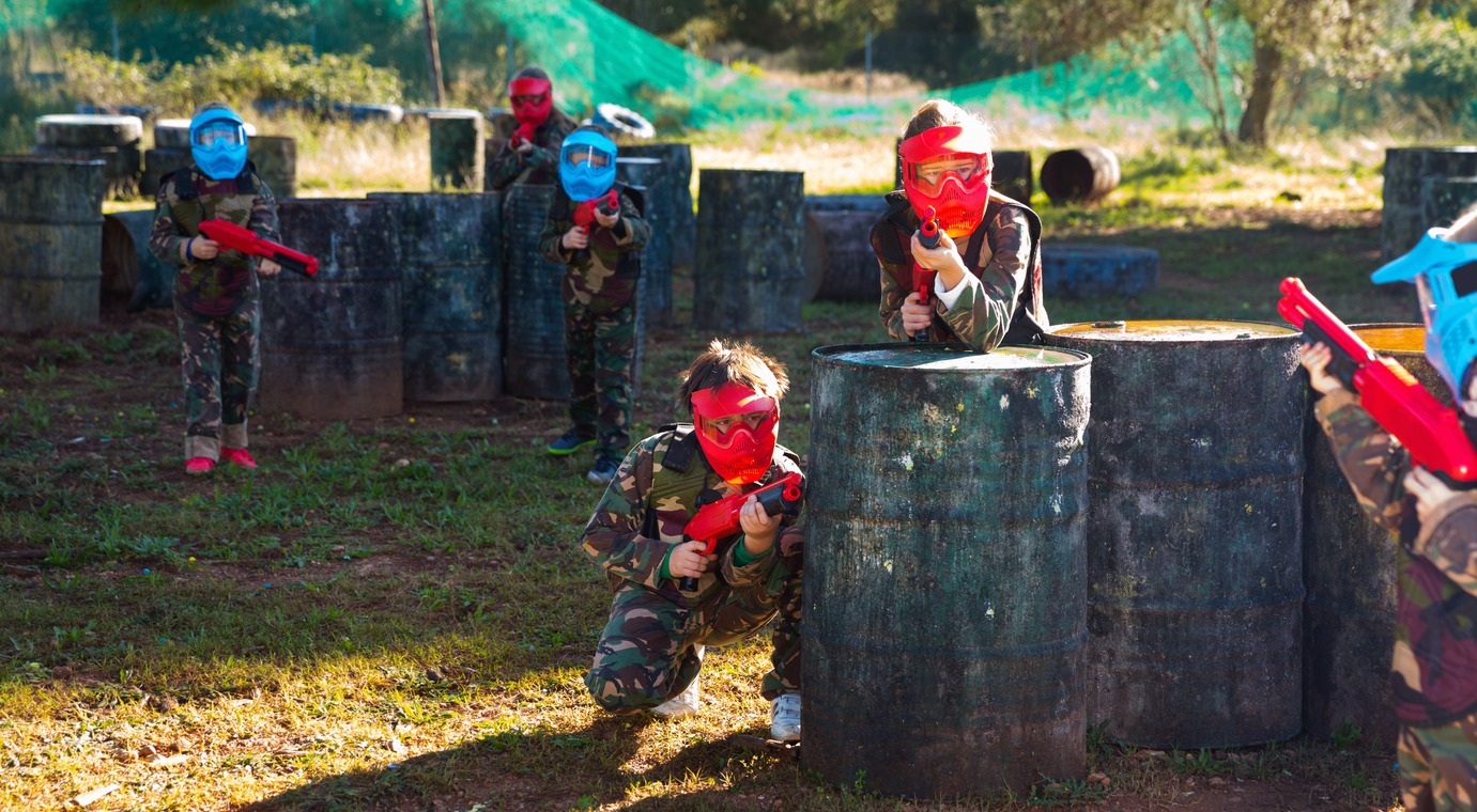 Children paintball players of opposite teams playing in shootout outdoors