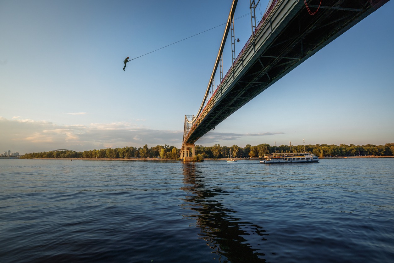 Man bungee jumping on Parkovy pedestrian bridge over Dnieper River - Kiev, Ukraine