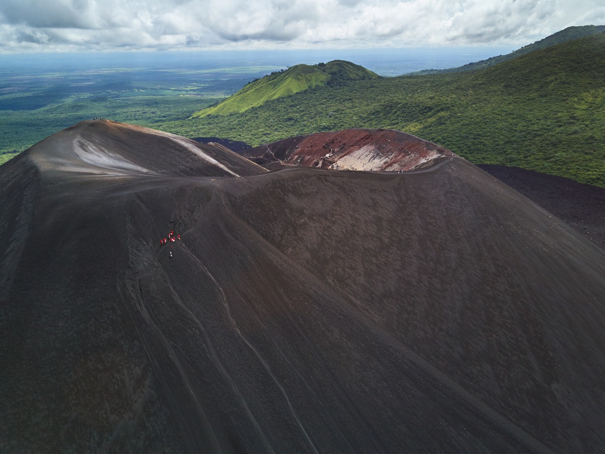 People on Cerro Negro volcano crater sliding on board activity aerial view