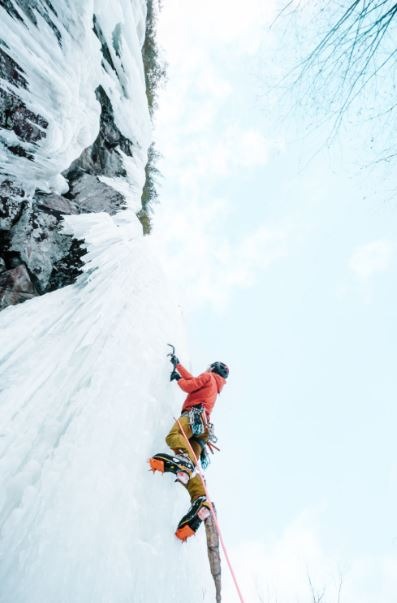 Person Scaling Ice Wall in Mountains