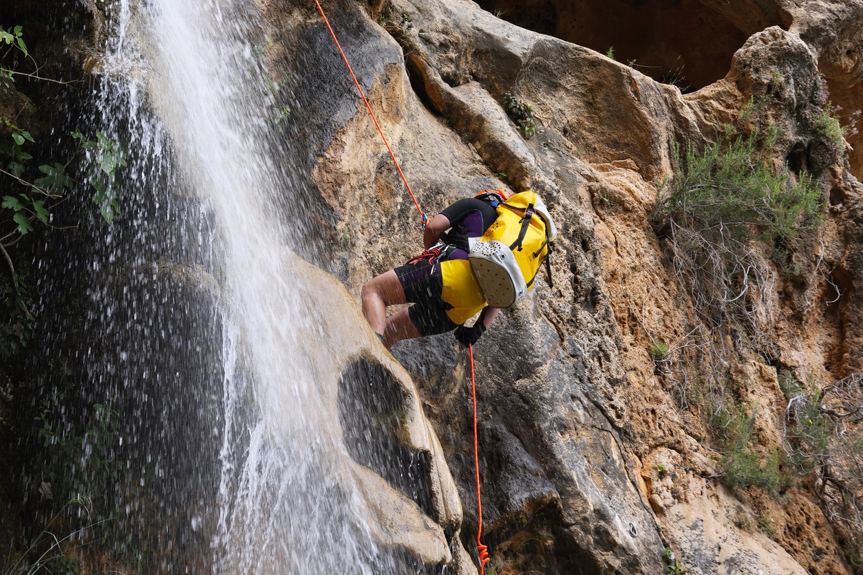 Young Lady with safety equipment abseiling through a waterfall