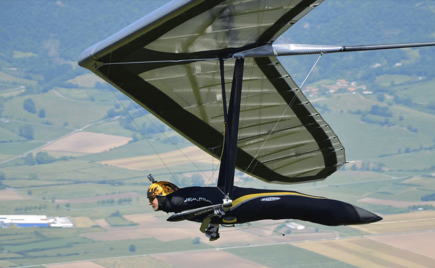 a person hang gliding, large hang glider, large fields